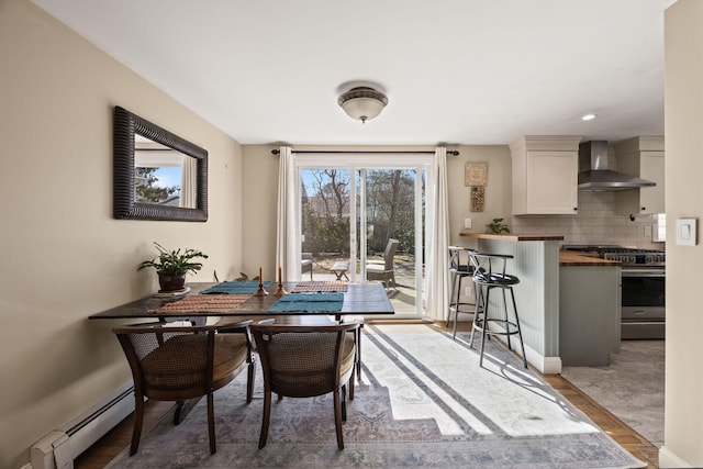 dining room featuring a baseboard heating unit, baseboards, and wood finished floors