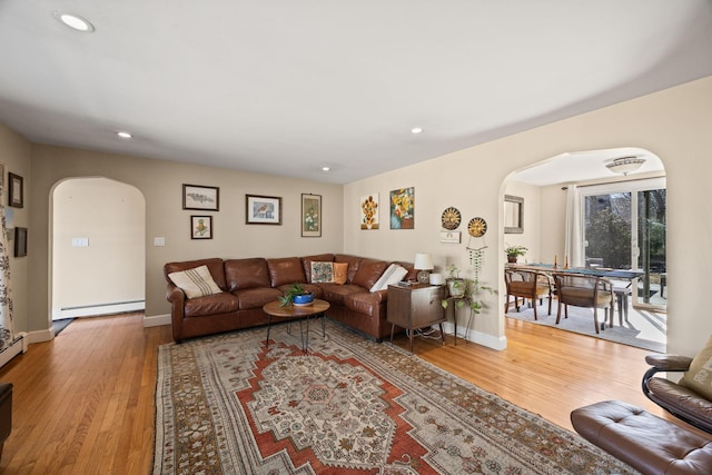 living area featuring light wood-type flooring, recessed lighting, arched walkways, a baseboard radiator, and baseboards