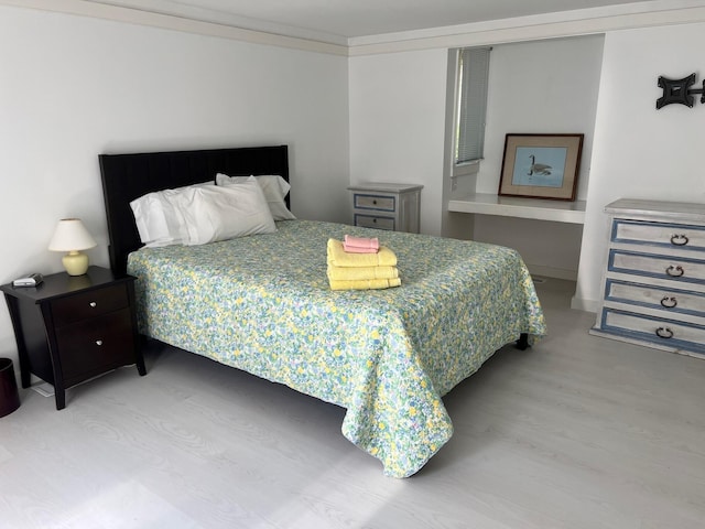 bedroom with light hardwood / wood-style flooring and ornamental molding