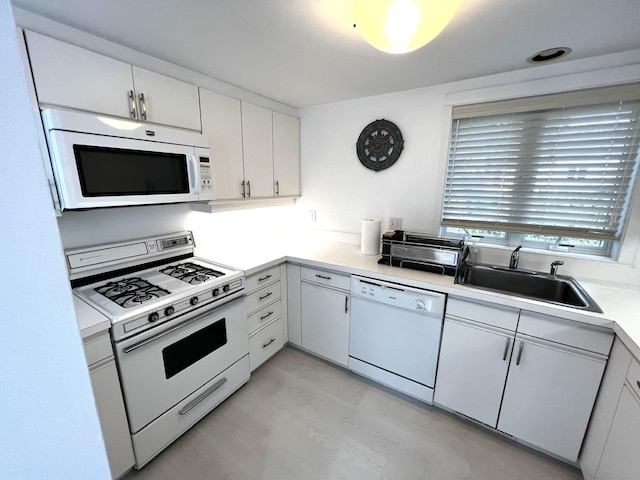 kitchen with sink, white appliances, and white cabinetry