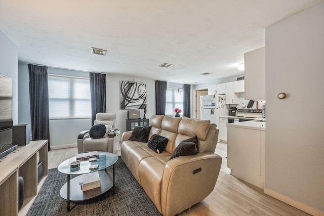 living area featuring visible vents, baseboards, and light wood finished floors