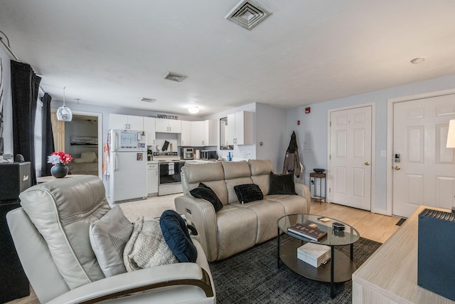 living room with visible vents and light wood-style flooring