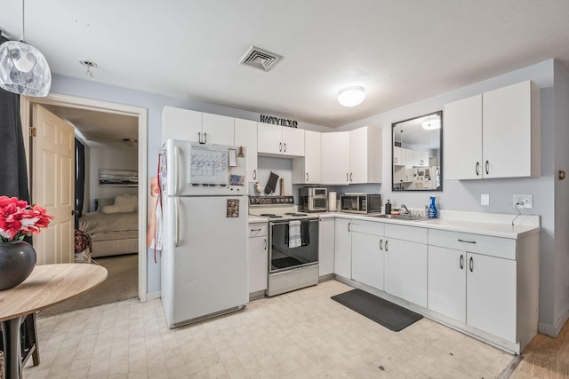 kitchen featuring visible vents, range with electric cooktop, light floors, light countertops, and freestanding refrigerator