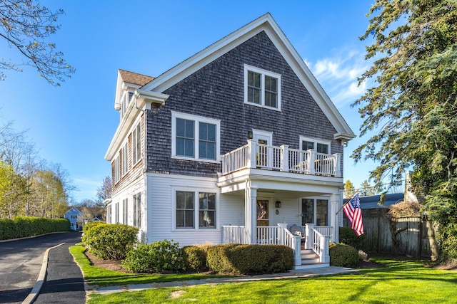 480 Main St Unit 1U, Falmouth, MA 02540 - shingle-style home with a balcony, fence, covered porch, aphalt driveway, and a front lawn