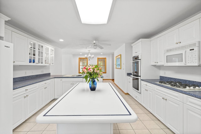 kitchen with a kitchen island, light tile patterned flooring, white appliances, and white cabinetry