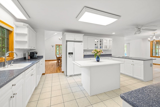 kitchen with white cabinets, a kitchen island, white refrigerator with ice dispenser, sink, and light tile patterned floors