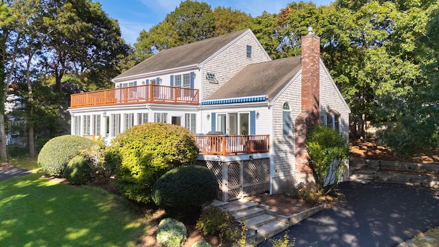 rear view of property featuring a balcony, a wooden deck, and a yard