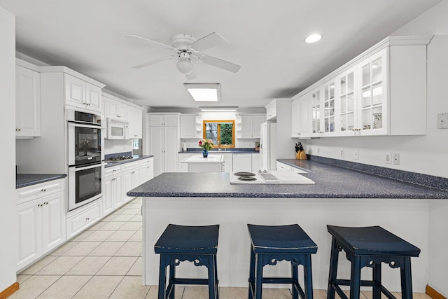 kitchen featuring white cabinetry, stainless steel appliances, a kitchen breakfast bar, kitchen peninsula, and light tile patterned floors