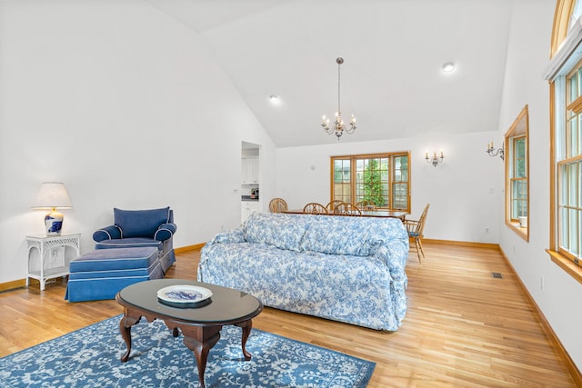 living room with light wood-type flooring, high vaulted ceiling, and a notable chandelier