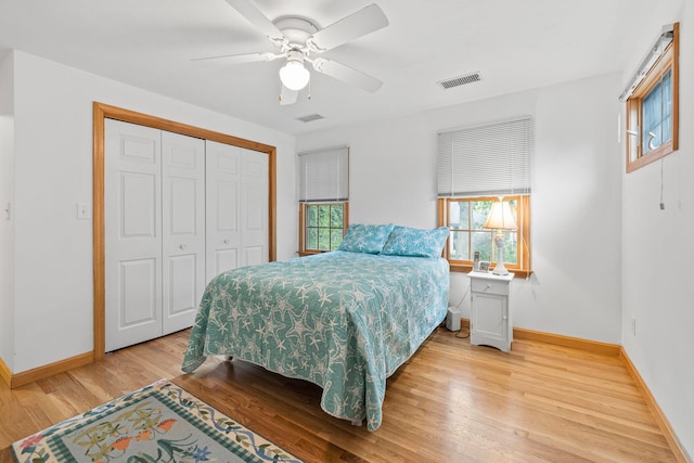 bedroom with ceiling fan, multiple windows, light hardwood / wood-style flooring, and a closet