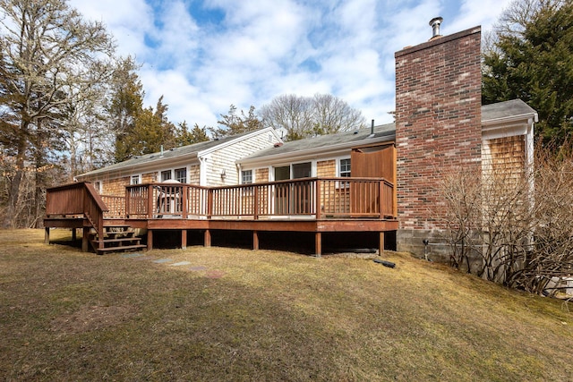 rear view of property with a wooden deck, a lawn, and a chimney