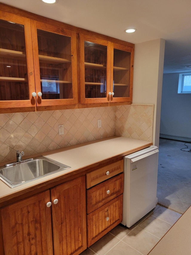 kitchen with brown cabinets, a sink, light countertops, baseboard heating, and dishwasher