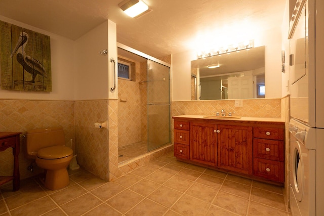 bathroom with tile patterned flooring, a shower stall, stacked washer and clothes dryer, tile walls, and toilet