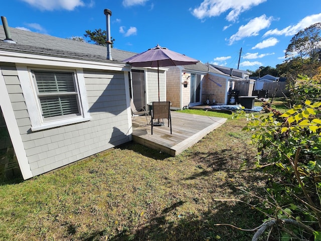 rear view of house with a wooden deck and a yard