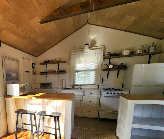 kitchen with wooden ceiling, white appliances, a breakfast bar, and vaulted ceiling