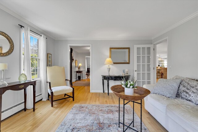living area with wood finished floors, crown molding, and a baseboard heating unit