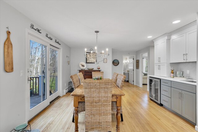 dining space with beverage cooler, a chandelier, light wood-style floors, recessed lighting, and baseboards
