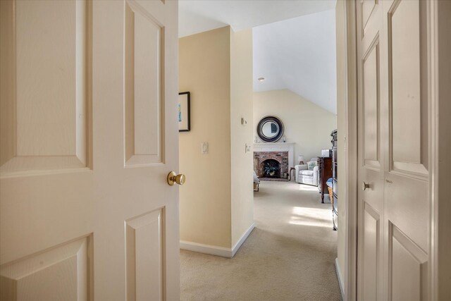 hallway featuring light carpet, lofted ceiling, and baseboards