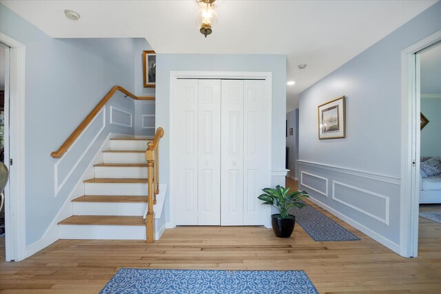 foyer entrance featuring wood finished floors, stairway, a wainscoted wall, a decorative wall, and recessed lighting