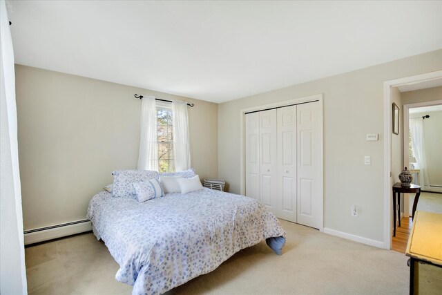 bedroom featuring a baseboard heating unit, a closet, light carpet, and baseboards
