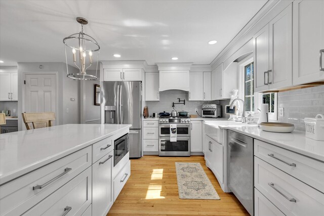 kitchen featuring appliances with stainless steel finishes, a sink, tasteful backsplash, light countertops, and recessed lighting