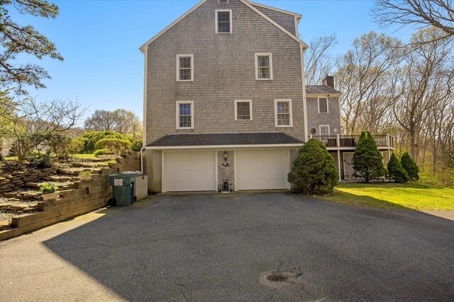 view of property exterior with driveway, a chimney, and a garage