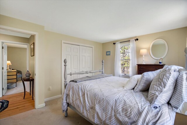 bedroom featuring a closet, light carpet, and baseboards