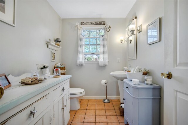 half bathroom with toilet, tile patterned floors, and baseboards