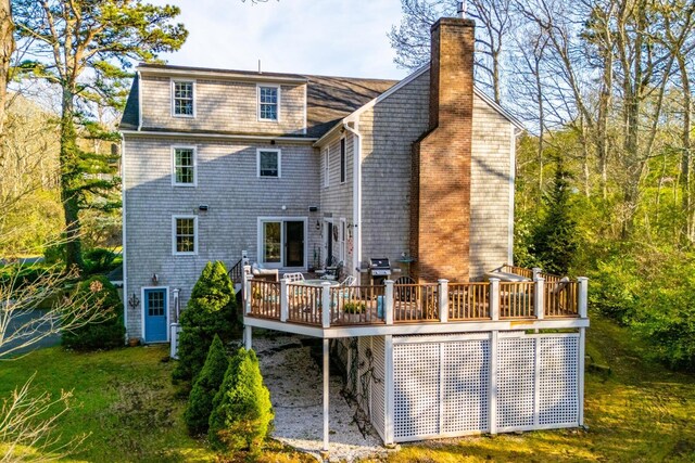 rear view of property featuring a wooden deck, a chimney, and a shingled roof