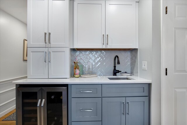 indoor wet bar featuring wine cooler, tasteful backsplash, and wood finished floors