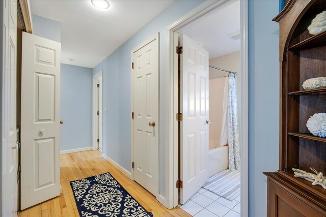 hallway featuring light wood finished floors and baseboards