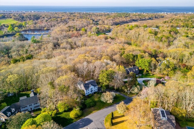 aerial view of property and surrounding area with a nearby body of water and a heavily wooded area