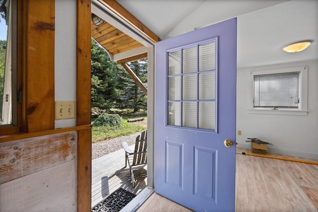 doorway with light wood-type flooring and vaulted ceiling