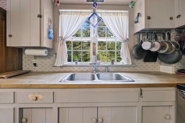 kitchen featuring butcher block counters, a sink, tasteful backsplash, and white cabinets
