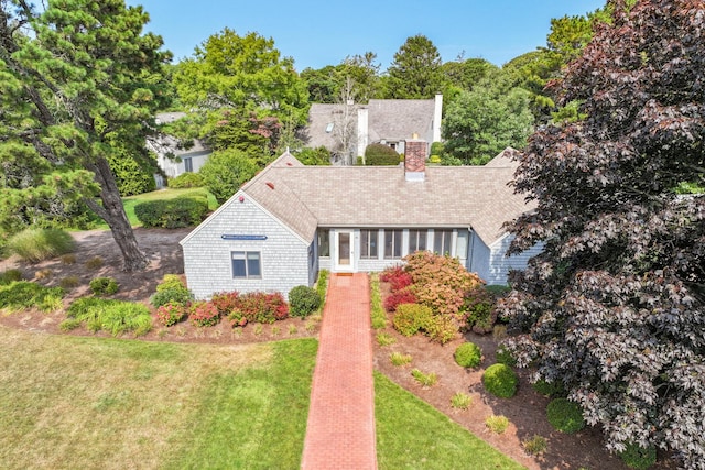 view of front of property with a chimney, a front yard, and a sunroom
