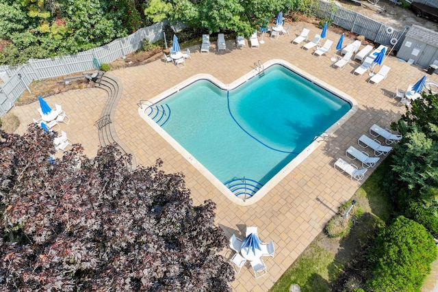 community pool with a patio area and fence