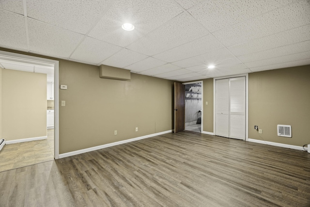 basement featuring hardwood / wood-style flooring and a paneled ceiling