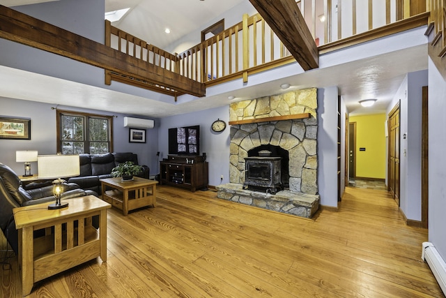 living room with light wood-type flooring, a wall mounted AC, a baseboard radiator, and baseboards