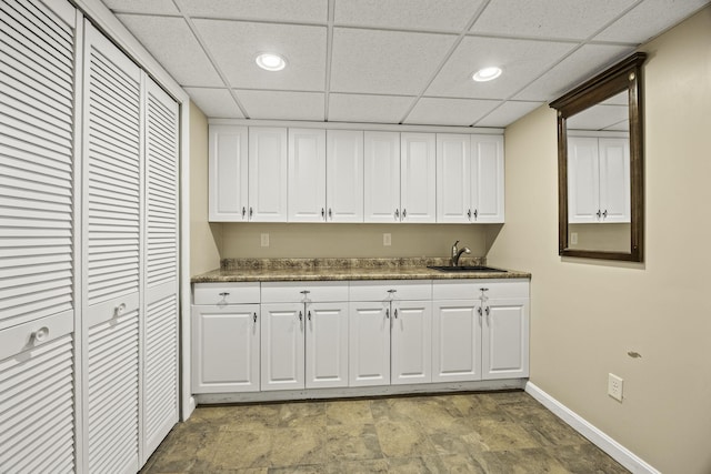 kitchen with dark stone countertops, sink, and white cabinets