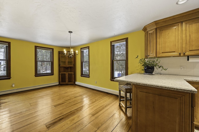 dining area with a baseboard radiator, light hardwood / wood-style floors, and a chandelier