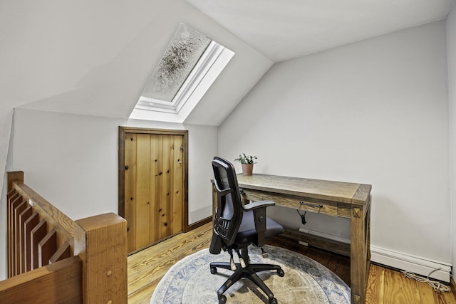 office with hardwood / wood-style flooring and lofted ceiling with skylight