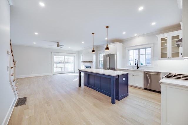 kitchen featuring sink, white cabinetry, hanging light fixtures, appliances with stainless steel finishes, and a kitchen island