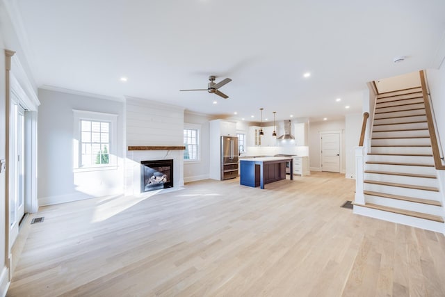 unfurnished living room featuring ornamental molding, a wealth of natural light, a fireplace, and light hardwood / wood-style floors