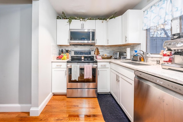 kitchen featuring sink, light wood-type flooring, white cabinetry, and appliances with stainless steel finishes