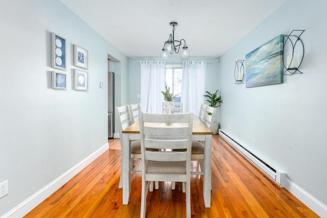 dining area featuring light wood-type flooring, an inviting chandelier, and baseboard heating