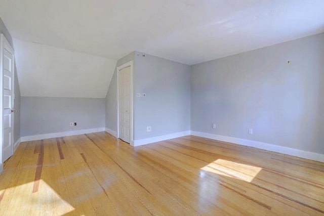 additional living space with light hardwood / wood-style flooring and vaulted ceiling