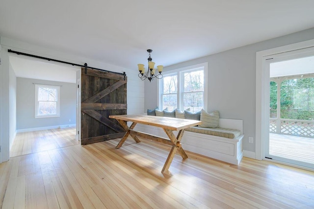 dining room with light hardwood / wood-style flooring, a barn door, and a chandelier