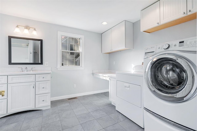 washroom featuring light tile patterned floors, cabinets, washer and clothes dryer, and sink