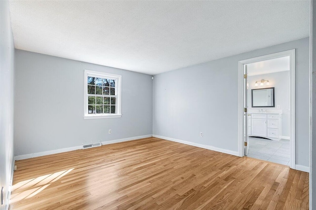 spare room with light hardwood / wood-style floors and a textured ceiling