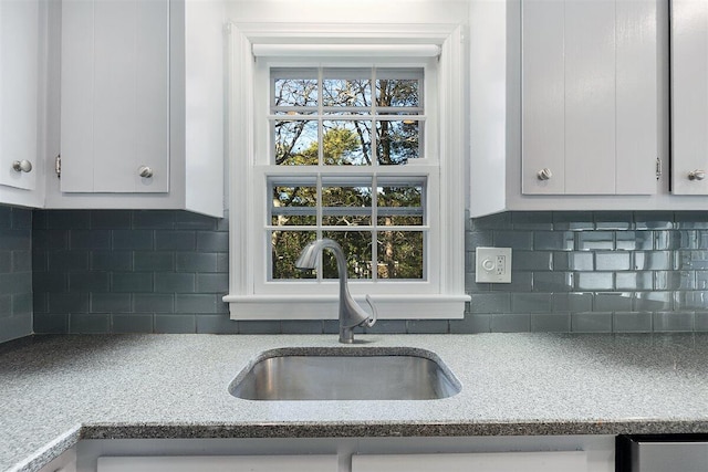 kitchen featuring sink, backsplash, white cabinets, and light stone countertops